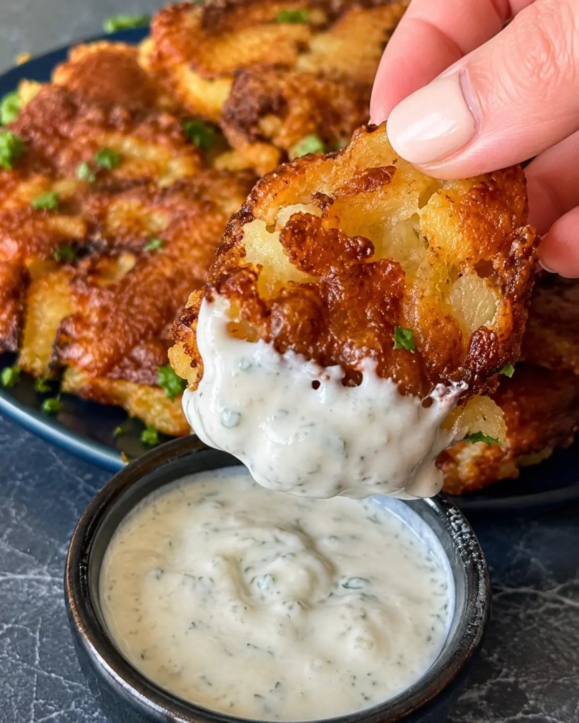 Crispy cheesy smashed potato dipped into creamy garlic herb sauce