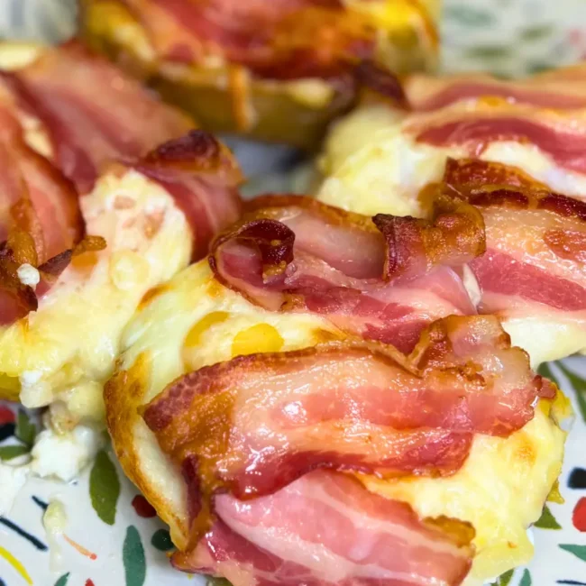 Homemade cheesy potato boats with bacon and baked eggs served on a decorative plate.