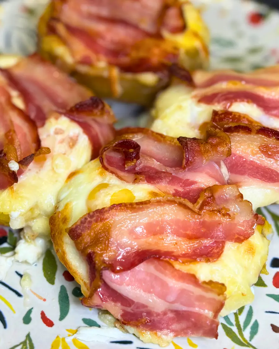 Homemade cheesy potato boats with bacon and baked eggs served on a decorative plate.