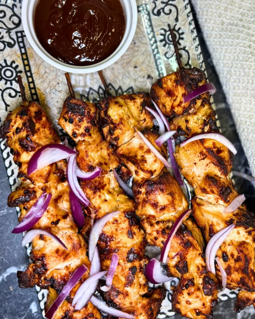 Golden air fryer chicken skewers served with sliced red onion and barbecue dipping sauce