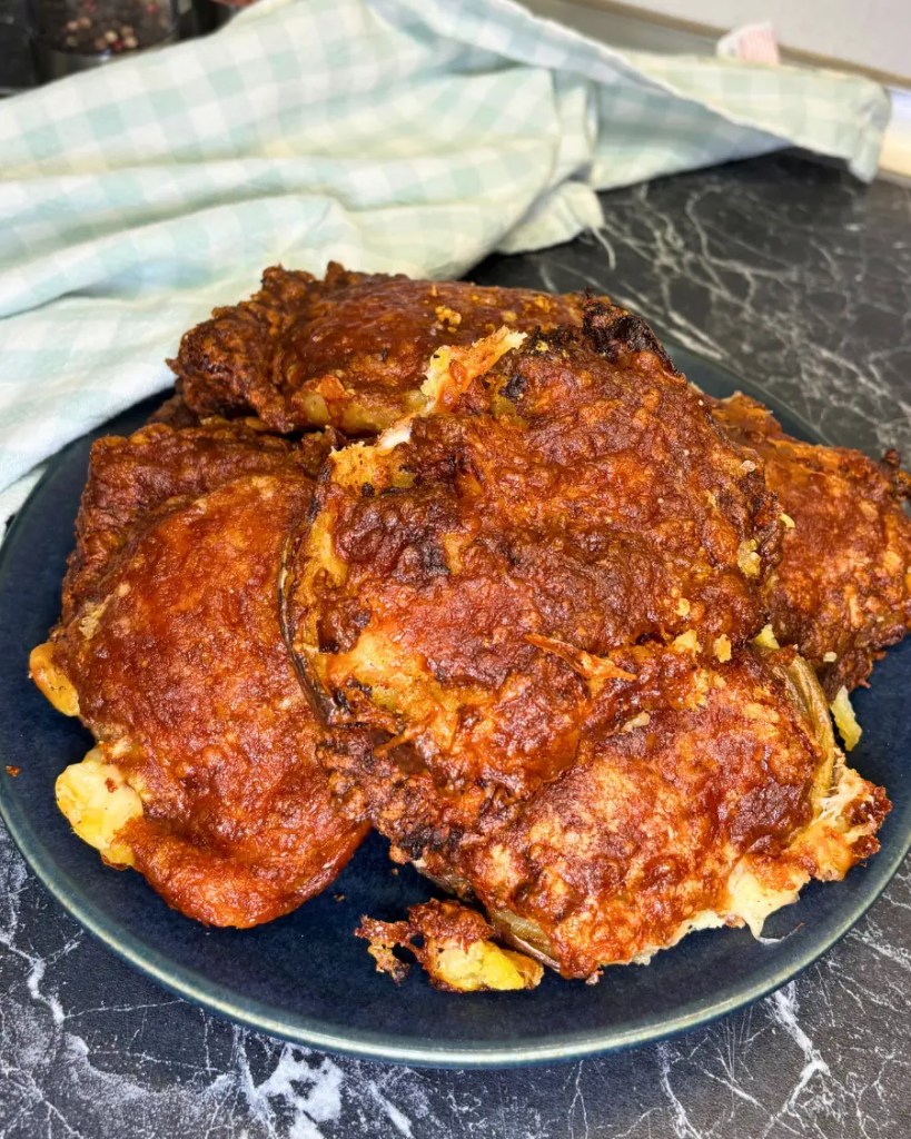 Plate of garlic parmesan smashed potatoes cooked in the air fryer until crispy and golden brown