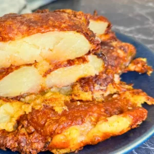 Side view of crispy air fryer smashed potatoes with cheesy golden crust and soft potato layers inside