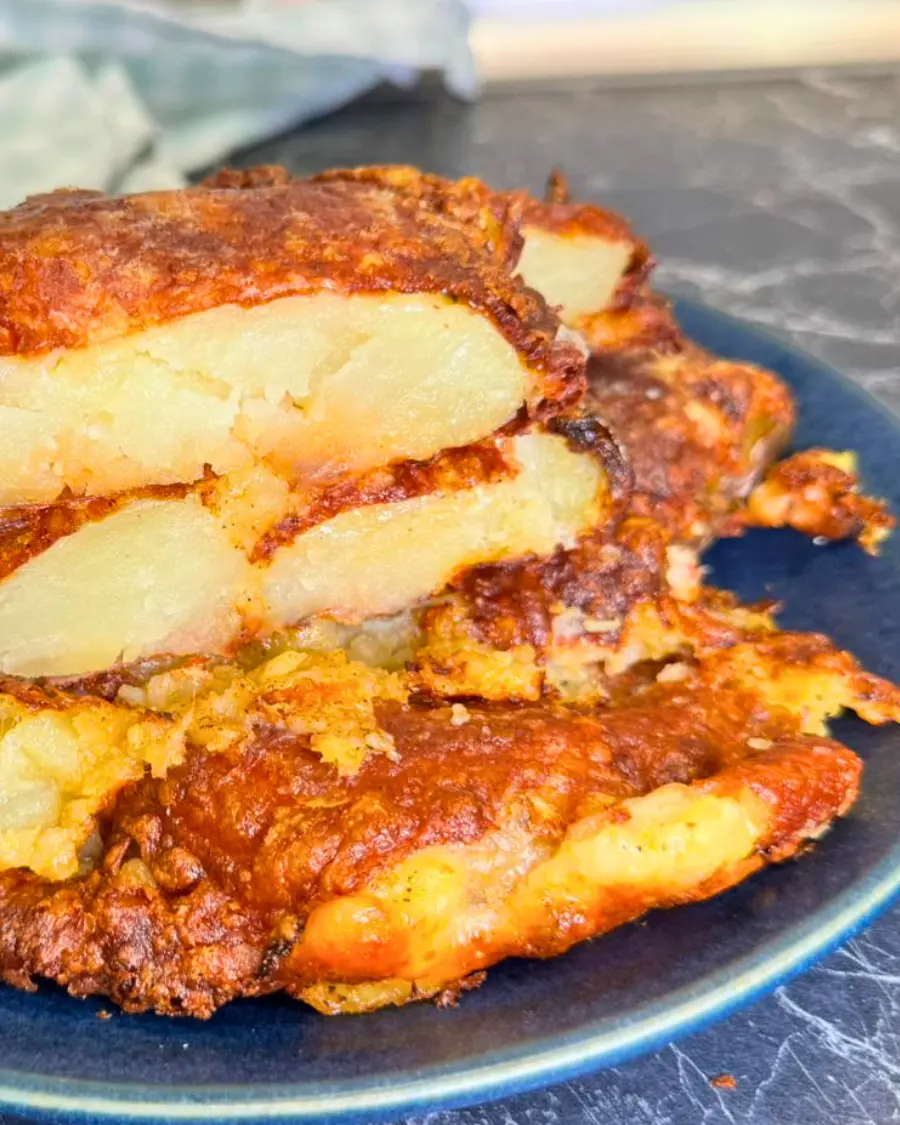 Side view of crispy air fryer smashed potatoes with cheesy golden crust and soft potato layers inside