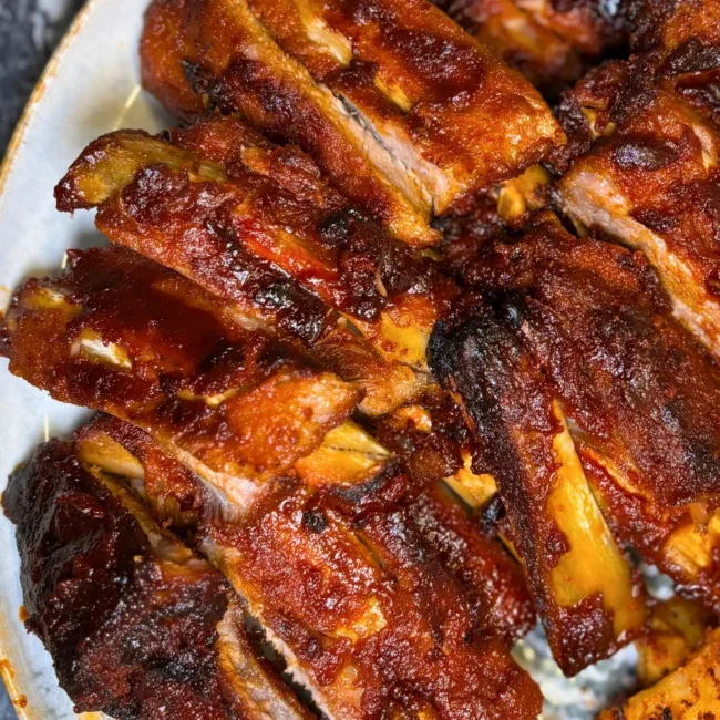 Close-up of tender sticky pork ribs coated in a rich honey soy glaze with crispy roasted potatoes.