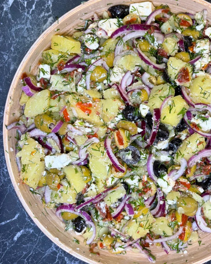 Close up of Mediterranean potato feta salad with olives, red onion, dill, and sun dried tomatoes.