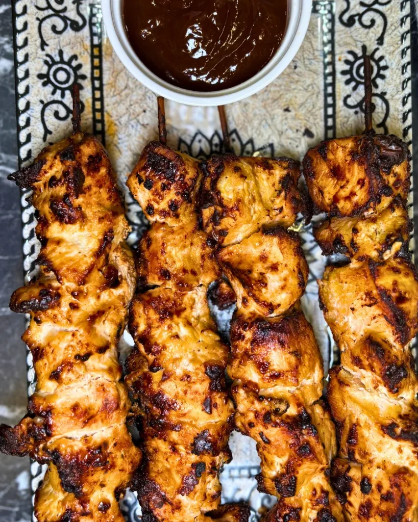 Tender air fryer chicken skewers dipped in barbecue sauce and topped with red onion slices