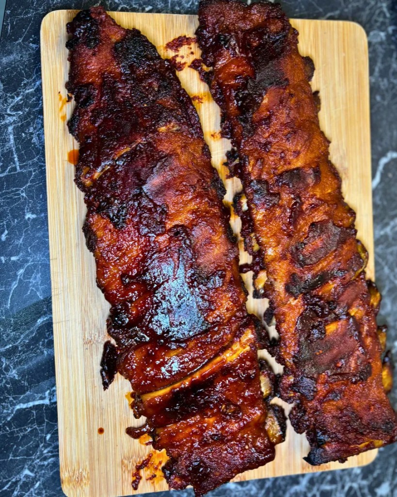 Oven baked sticky honey soy pork ribs with a dark caramelized glaze served on a wooden cutting board.