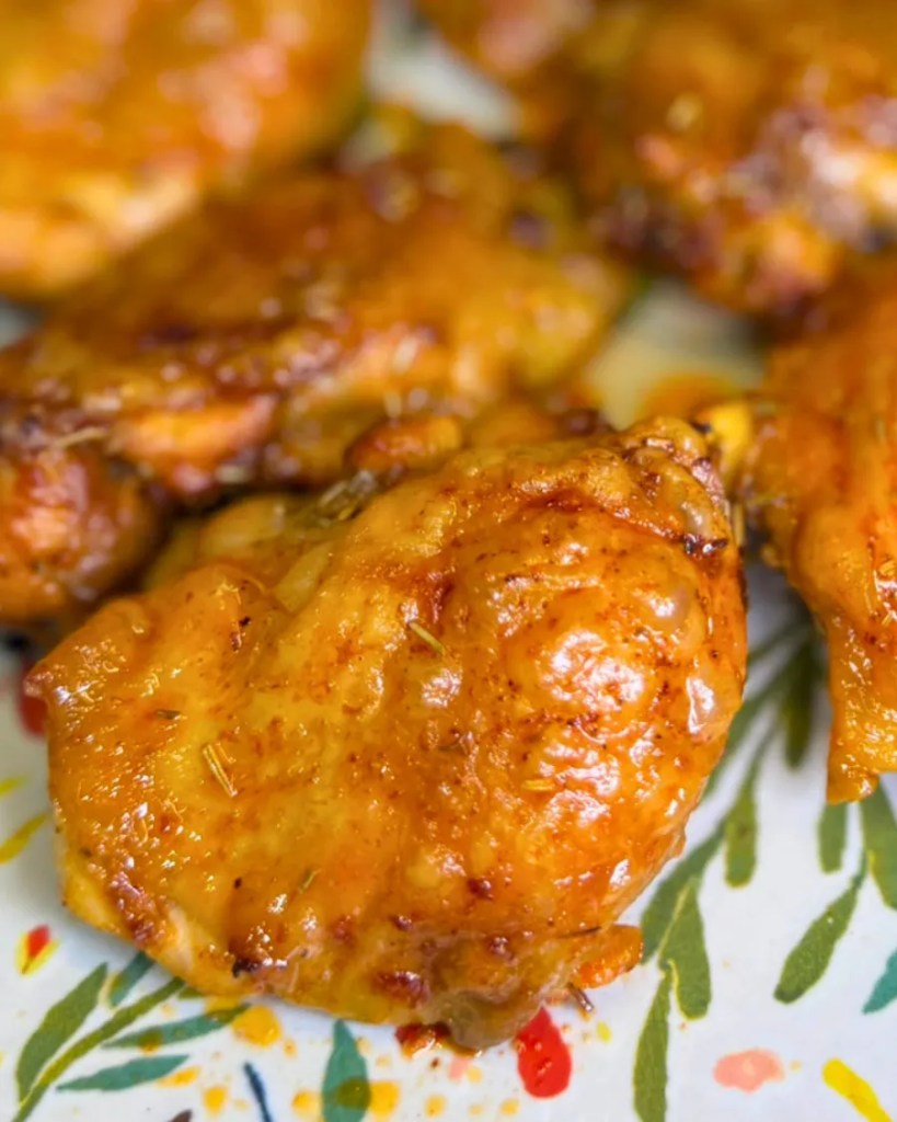 Close-up of a crispy honey mustard chicken thigh with golden skin and juicy meat.