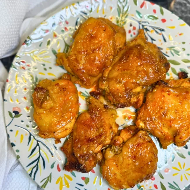 Golden brown honey mustard baked chicken thighs served on a plate after baking in the oven.