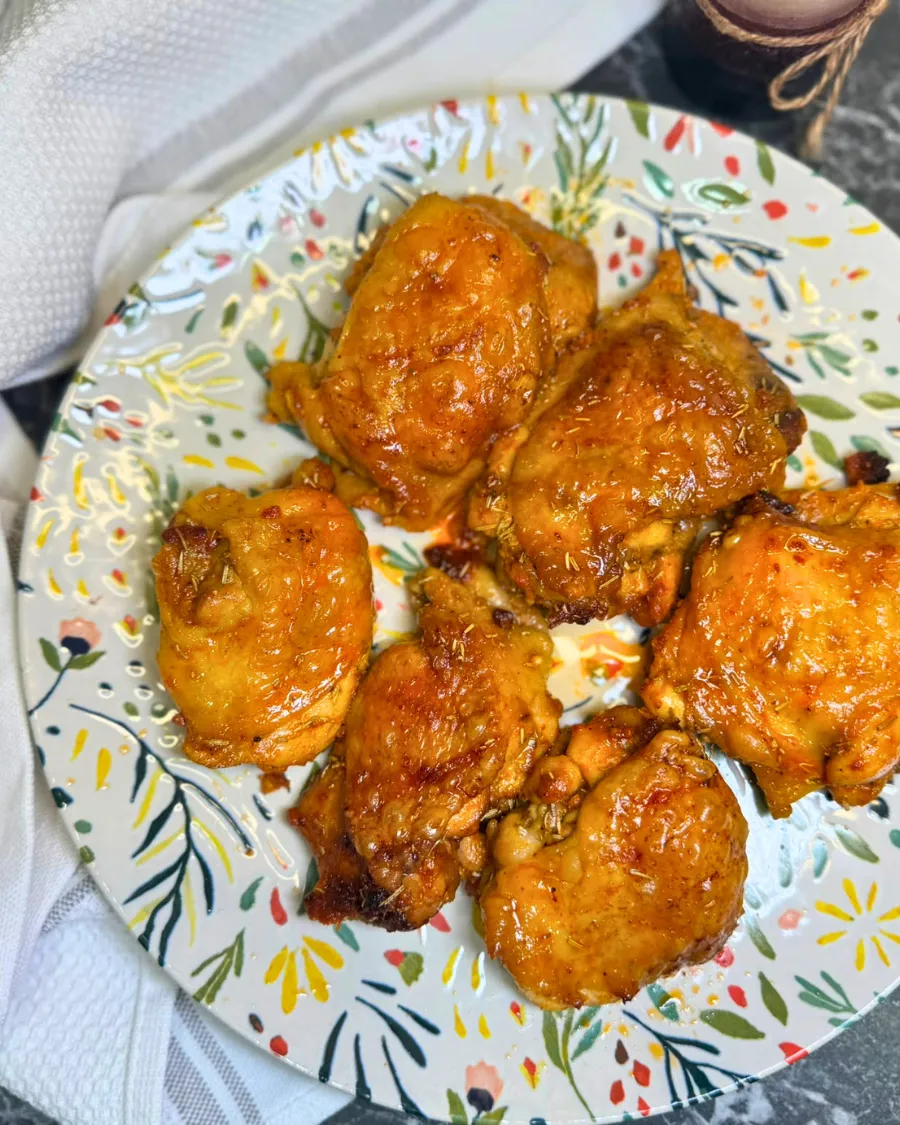 Golden brown honey mustard baked chicken thighs served on a plate after baking in the oven.