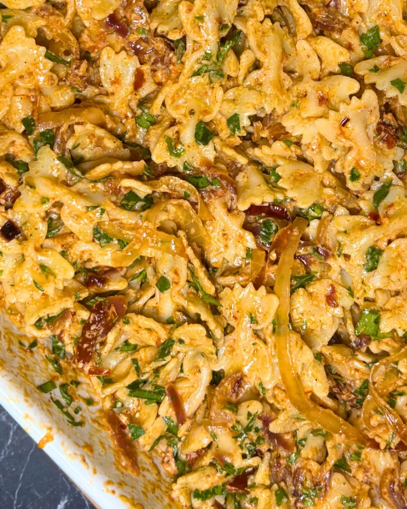 Creamy onion pasta with sun-dried tomatoes and fresh parsley served on a turquoise plate