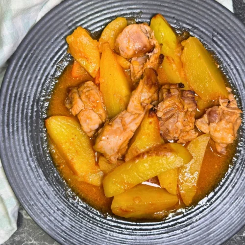 Plate of oven-braised rabbit, potatoes, and carrots in a savory tomato sauce.