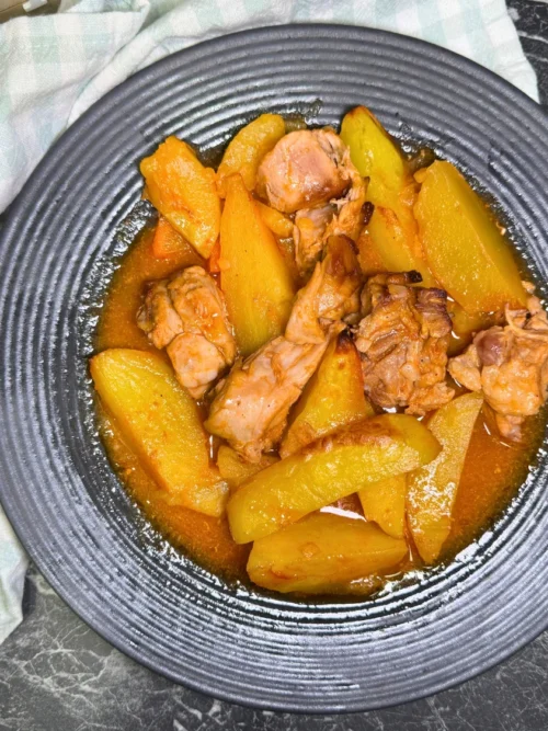 Plate of oven-braised rabbit, potatoes, and carrots in a savory tomato sauce.