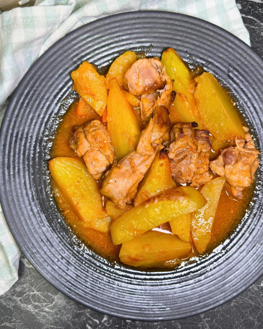 Plate of oven-braised rabbit, potatoes, and carrots in a savory tomato sauce.