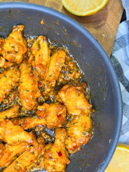 Sticky air fryer sweet chili chicken wings served on a plate with a fresh lemon wedge.