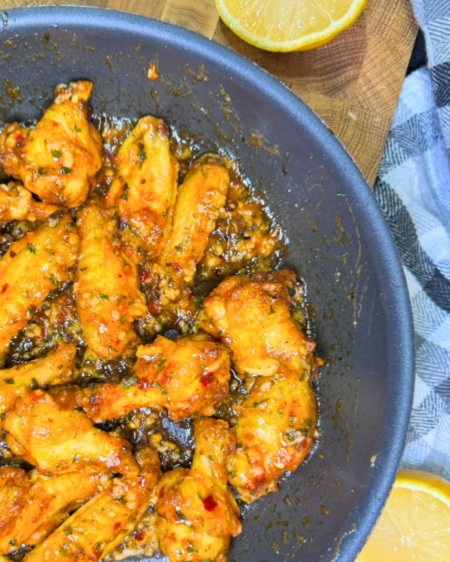 Sticky air fryer sweet chili chicken wings served on a plate with a fresh lemon wedge.