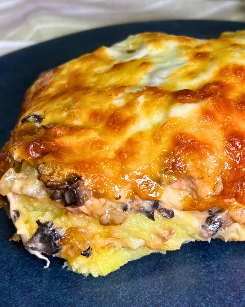 Side view of a homemade chicken and mushroom potato casserole showing mashed potatoes, creamy mushroom filling, and browned mozzarella cheese.