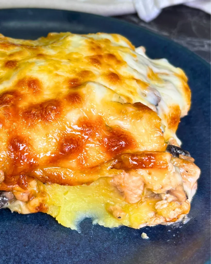 Close-up of a cheesy chicken and mushroom casserole slice with creamy mashed potatoes, tender chicken, and golden melted mozzarella.