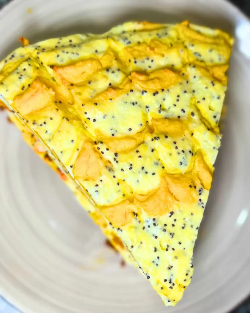 Slice of marble pumpkin and cottage cheese casserole on a white plate, showing golden pumpkin swirls and creamy cottage cheese with poppy seeds.